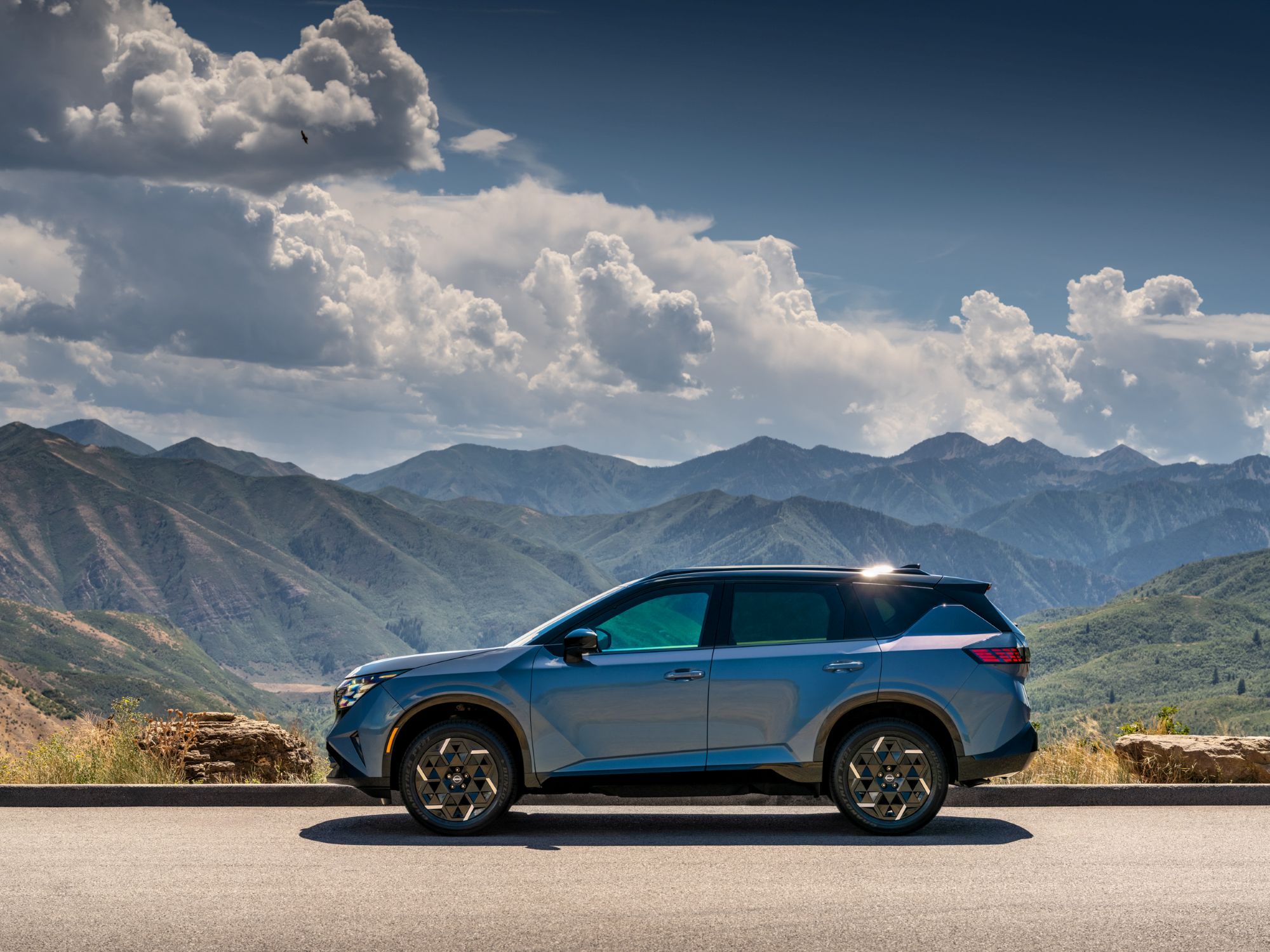 2027 Nissan Rogue Hybrid side view with mountain backdrop