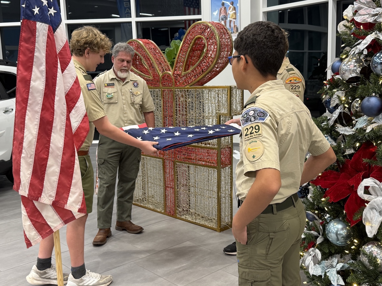 Scouts proudly raising the new American flag during the ceremony at the dealership