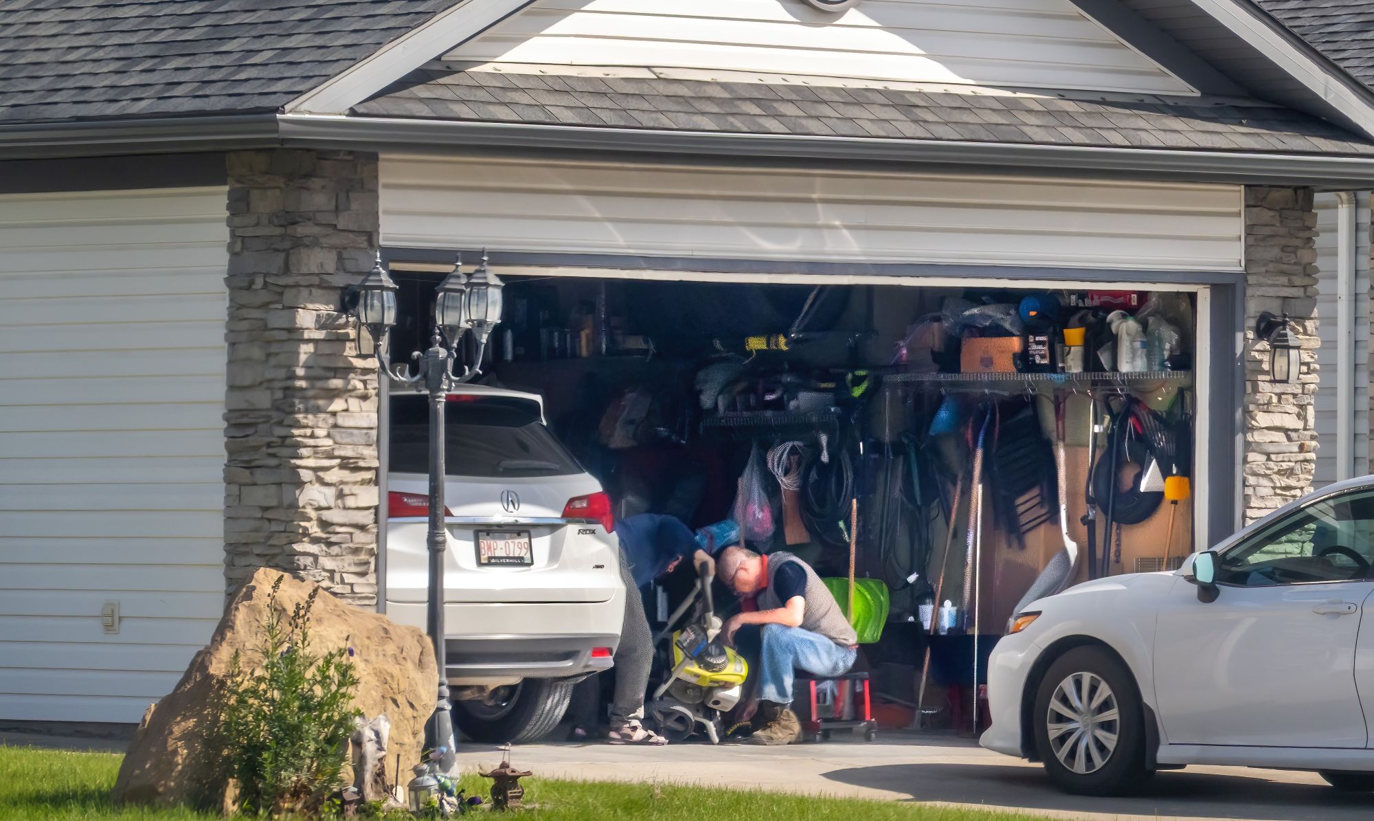 White Acura RDX parked inside a home garage with tools and storage shelves