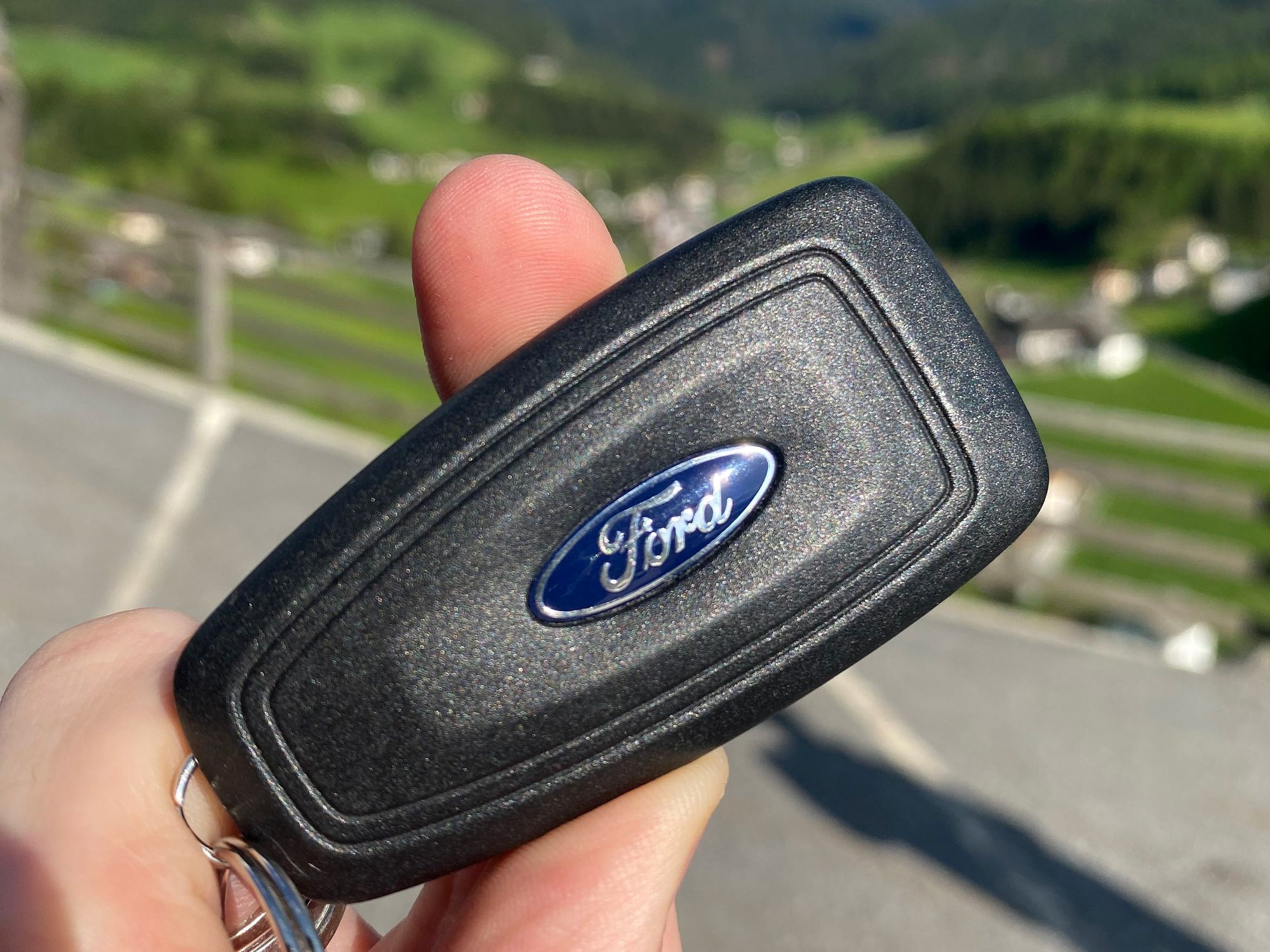 Hand holding a black Ford key fob with the blue Ford oval logo