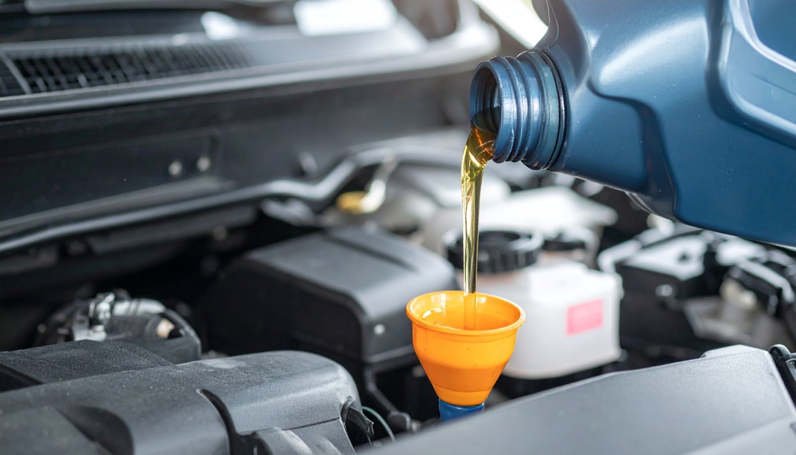 Technician pouring Nissan motor oil during an oil change